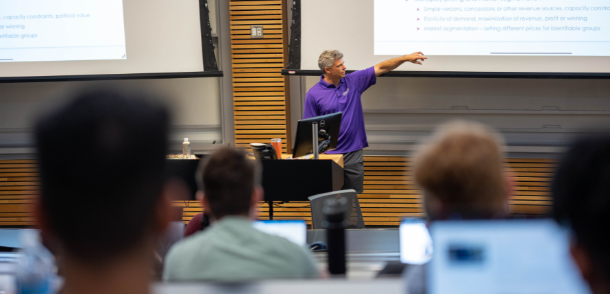 Professor pointing to screen in lecture hall