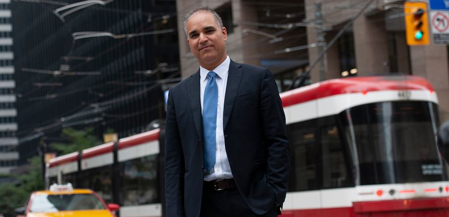 Man standing on a city street in front of a train car