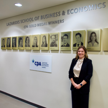 Nicole Cullen stands by her photo on the CPA Gold Medal wall in Lazaridis Hall