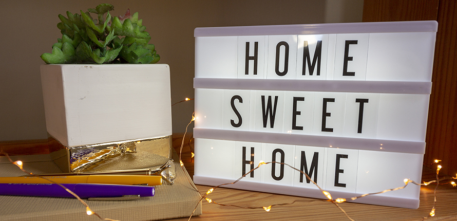Home Sweet Home sign with pens, books and lights on a desk