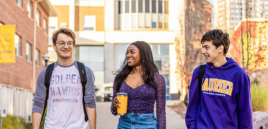 three students walking on Waterloo campus in fall