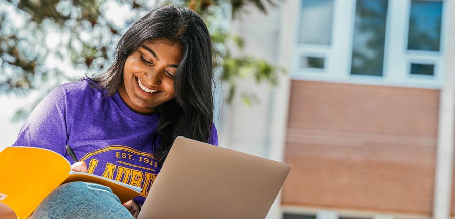 female student smiling taking notes